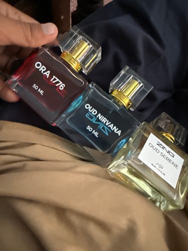 Customer holding the three perfume bottles from the OUD Supreme Bundle: Ora 1776, Oud Nirvana, and Oud Serene.