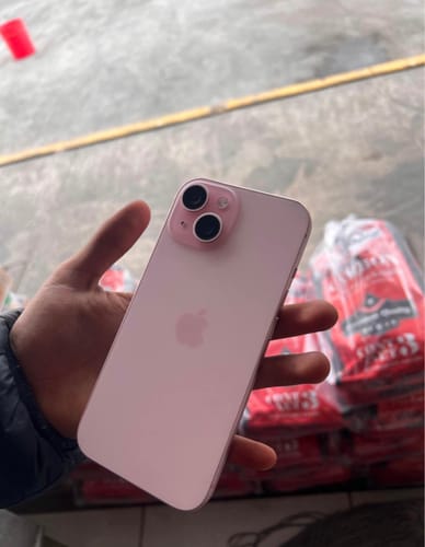 Cliente sosteniendo la parte trasera de un iPhone 15 de color rosa en la mano.