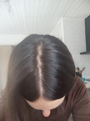 A reviewer's view from above of their shiny, dark brown hair after using Grey Cover.