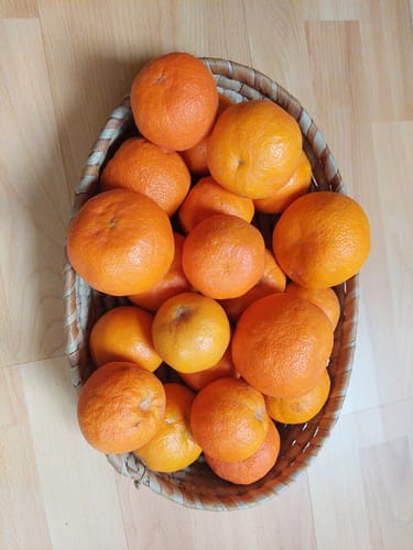 Ein Kunde zeigt einen geflochtenen Korb, der mit frischen Bio-Bitterorangen gefüllt ist.