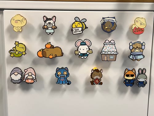Reviewer's Derpy Tiger Pin displayed with other cute pins on a metal cabinet.
