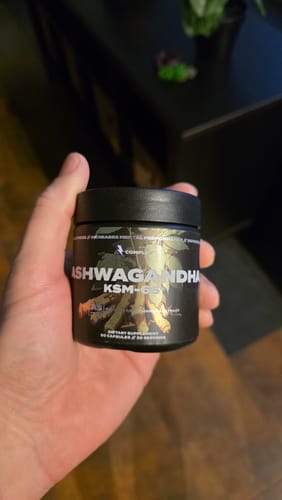 Customer holding a small black jar of Ashwagandha KSM-66 in their hand.