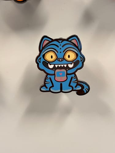 A close-up of the customer's blue Derpy Tiger Pin on a white surface.