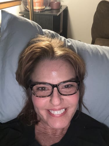 Reviewer with glasses smiling brightly, showing her teeth after using Pop On Veneers.