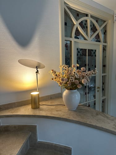 Recensent toont het Wax-arrangement in een witte vaas, stijlvol geplaatst op een marmeren aanrecht.
