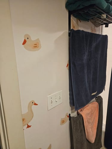 Customer's Daffy Wallpaper with a cute duck pattern installed on a bathroom wall next to a light switch and towels.