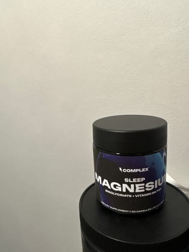 Reviewer's black jar of Complex Sleep Magnesium supplement resting on another container.
