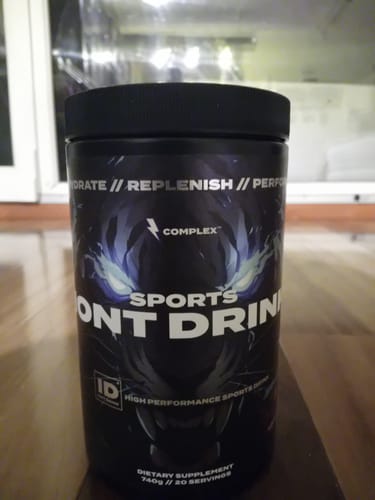 Customer's black tub of Sports Iont Drink supplement sitting on a wooden surface.