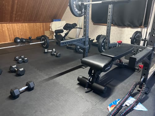 Kundenbild der stabilen B6 Hantelbank in einem Home-Gym, aufgestellt neben einem Power Rack und Hanteln.
