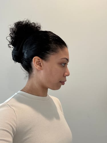 Reviewer in profile with the black cloud clip securing thick, curly hair in a high bun.