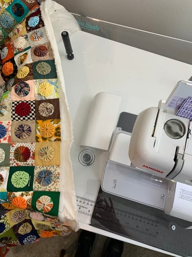 Customer's Sew Steady extension table supporting a colorful quilt next to a sewing machine.