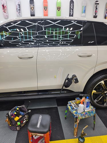 Customer showing a paintless dent repair tool on a white car door, using Tequila Ice Glue on a yellow pull tab.