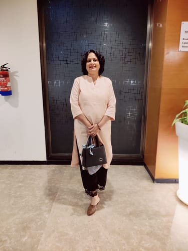 Reviewer's aunt smiling while wearing the salmon pink long kurta indoors.