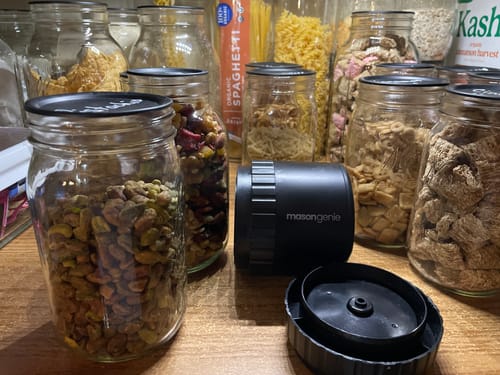 Customer's black Mason Genie Vacuum Sealer Kit on a pantry shelf next to sealed jars of dry goods.