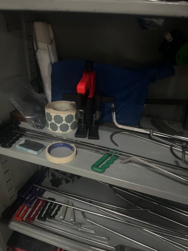 Reviewer's Camauto Smart Mini Lifter with a red handle on a shelf with other auto body tools.