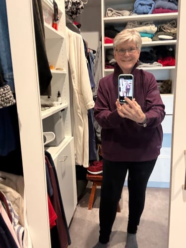 Reviewer in a closet wearing the majestic purple Quinn Ribbed 1/4 Zip, showing its oversized fit and stand-up collar.
