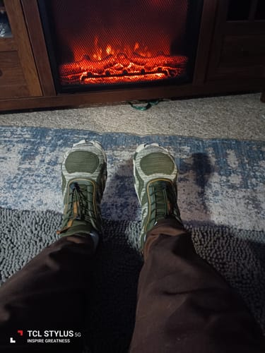 Reviewer wearing the green camouflage Active II - Barefoot Shoes while relaxing in front of a fireplace.