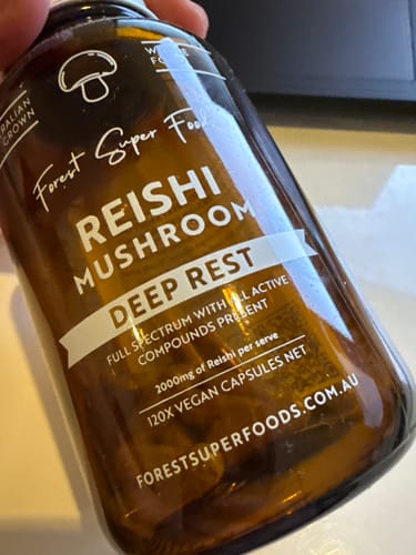 A customer holds a brown glass bottle of Reishi Mushroom Deep Rest from the Australian Grown Mushroom Bundle.