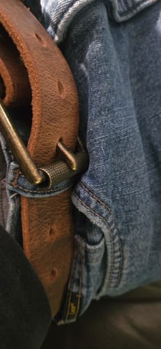 Close-up of a reviewer wearing the brown, distressed Crazy Horse leather belt with jeans.