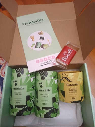Un cliente muestra el contenido de su pedido: dos botes de Té Matcha Premium, una muestra y una galleta en la caja.