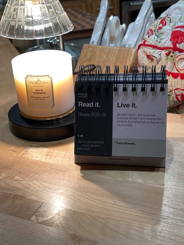 Reviewer's 'Read It, Live It' Calendar open on a wooden counter next to a lit white candle.