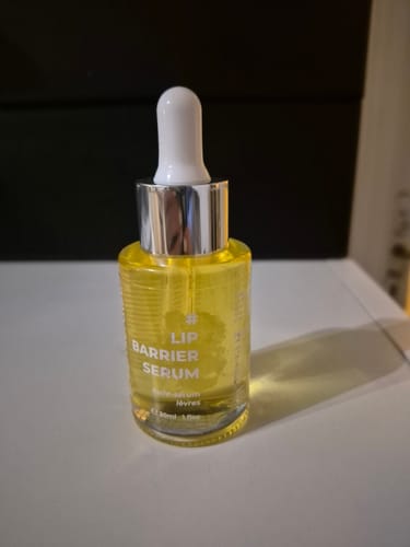 Client montrant le Lip Barrier Serum dans son flacon en verre, rempli du sérum-huile de couleur jaune.