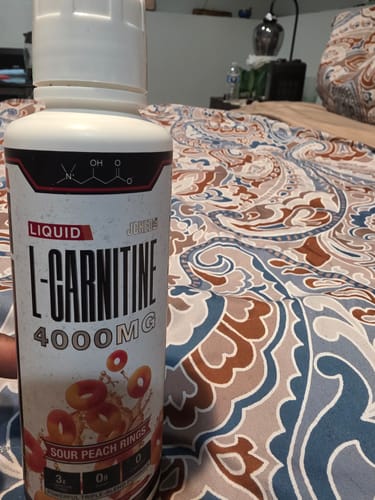 Customer holds up their bottle of Liquid L-Carnitine 4000MG, showing the Sour Peach Rings flavor.