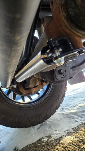 Close-up of the customer's new silver Low-Mount Steering Stabilizer installed on their truck's undercarriage.