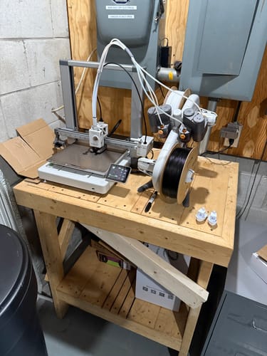 Customer's Bambu Lab A1 Combo 3D printer and AMS lite unit set up on a wooden workbench.