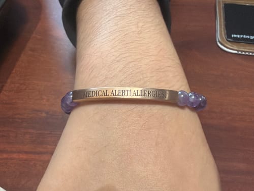 Customer wearing the custom Amethyst Bracelet with a metal plate engraved with 'MEDICAL ALERT! ALLERGIES'.