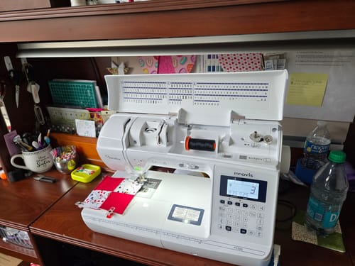 Reviewer's Brother Pacesetter PS500 sewing machine on a desk, in the middle of a red and white quilting project.