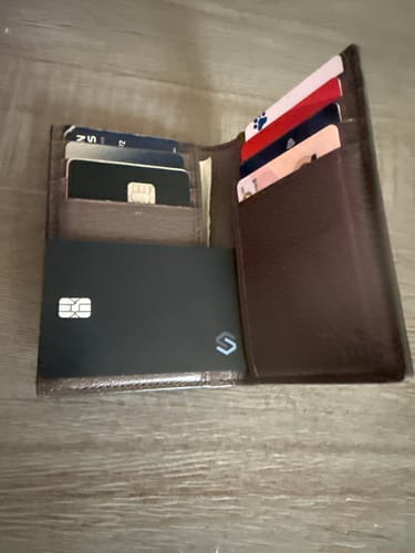 Customer's black Spotminders Tracking Card PRO shown inside a brown wallet with other cards.