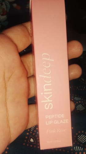 Close-up of a customer holding the pink box containing the Peptide Lip Glaze.