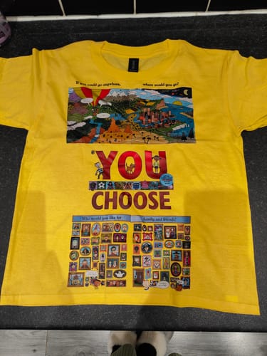 Reviewer's yellow kids t-shirt laid flat, showing a custom graphic from the book 'You Choose'.