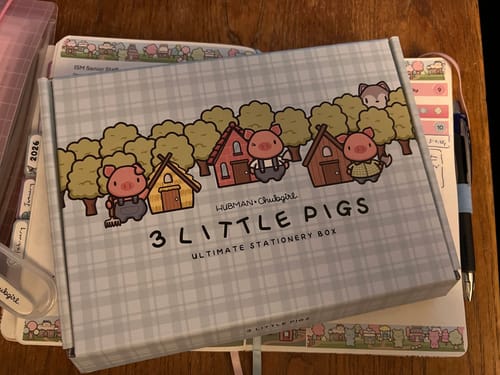 Customer's Ultimate Subscription box with the illustrated '3 Little Pigs' theme, sitting on a planner.