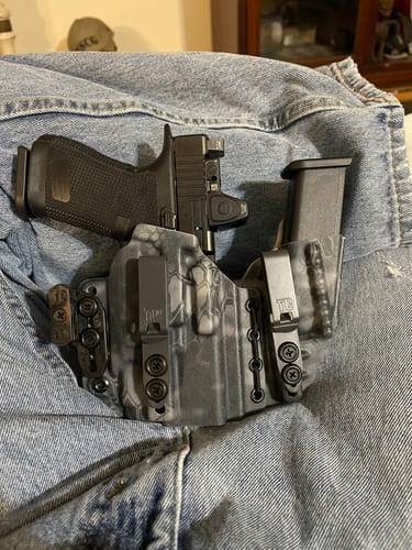 Reviewer's gray patterned AXIS ELITE holster holding a handgun and magazine, resting on blue jeans.