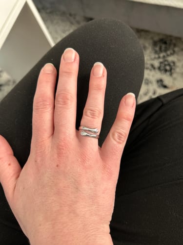 Reviewer's hand wearing a silver-colored ring designed to look like arms hugging a finger.