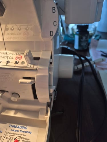 Reviewer's close-up of a Babylock serger showing the broken area where the bed cover attaches.