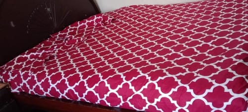 Customer's red and white patterned Red Pendora Fitted Sheet shown fitted on a bed.