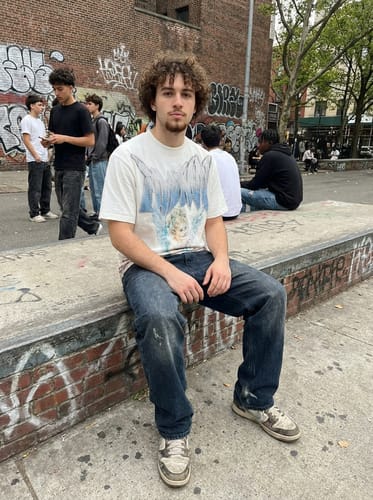 Reviewer wearing the white Retro Street Peace Dove Angel T-Shirt with blue jeans while sitting outdoors.