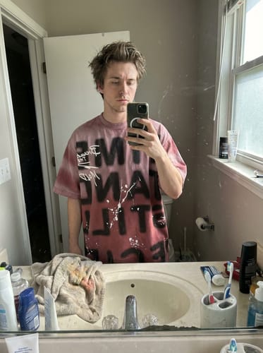 Customer taking a mirror selfie to show the relaxed fit of the graphic Ink Splash Letter Print T-shirt.