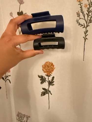Customer holding two different sized cloud clips, one navy and one black, for comparison.