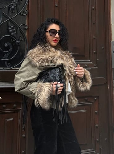 Customer holding the black Tassel Shoulder Bag, styled with a fur-collared jacket.