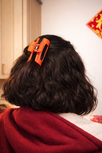 Customer from behind wearing an orange cloud clip in their dark wavy hair.