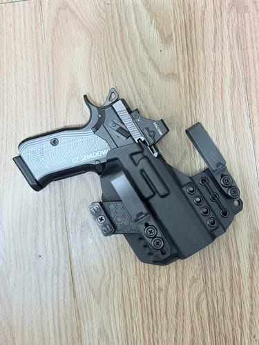 Customer's black XIPHOS ELITE holster holding a handgun with a grey grip on a light wood surface.