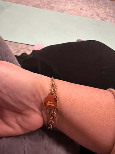 Customer wearing the Engravable Classic Chunky Disc Bracelet on their wrist, showing the personalized round charm with names.