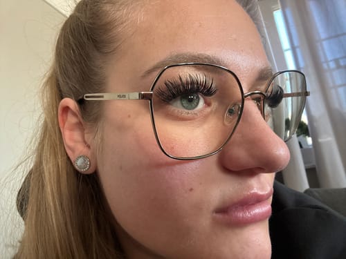 Kundin zeigt in einer Nahaufnahme die langen, voluminösen Wimpern des MIAMI BEACH STARTER KITs unter ihrer Brille.