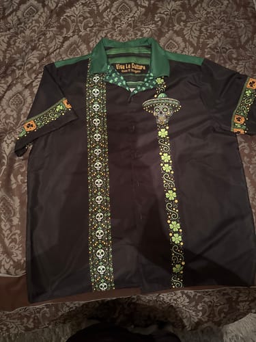 Customer's St. Patrick's Calavera Guayabera laid flat. The black shirt has green trim and panels with skulls and clovers.