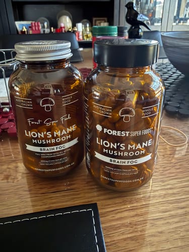 Customer's two amber bottles of Lion's Mane Mushroom Capsules sitting side-by-side on a wooden desk.
