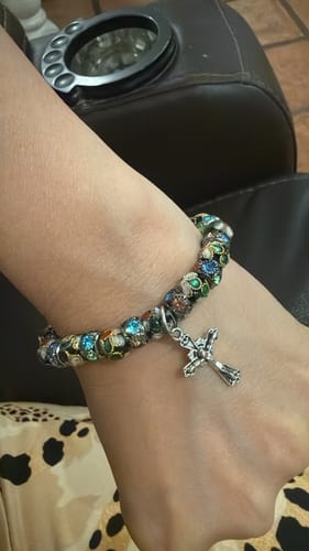 Reviewer's wrist wearing the Timeless Faith Bracelet, with colorful cloisonné beads and a silver cross charm.